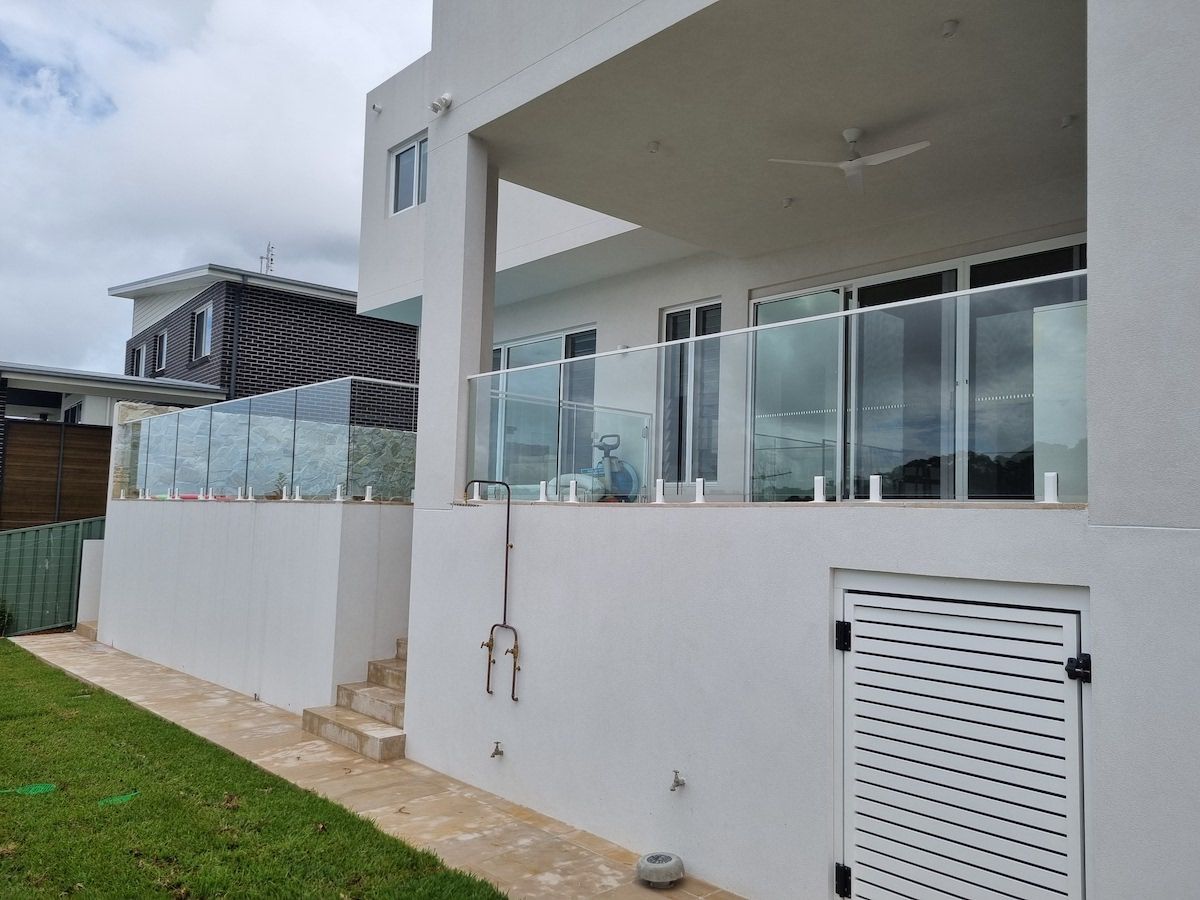 Man standing on a balcony with a glass railing — Glass Balustrades in Unanderra NSW
