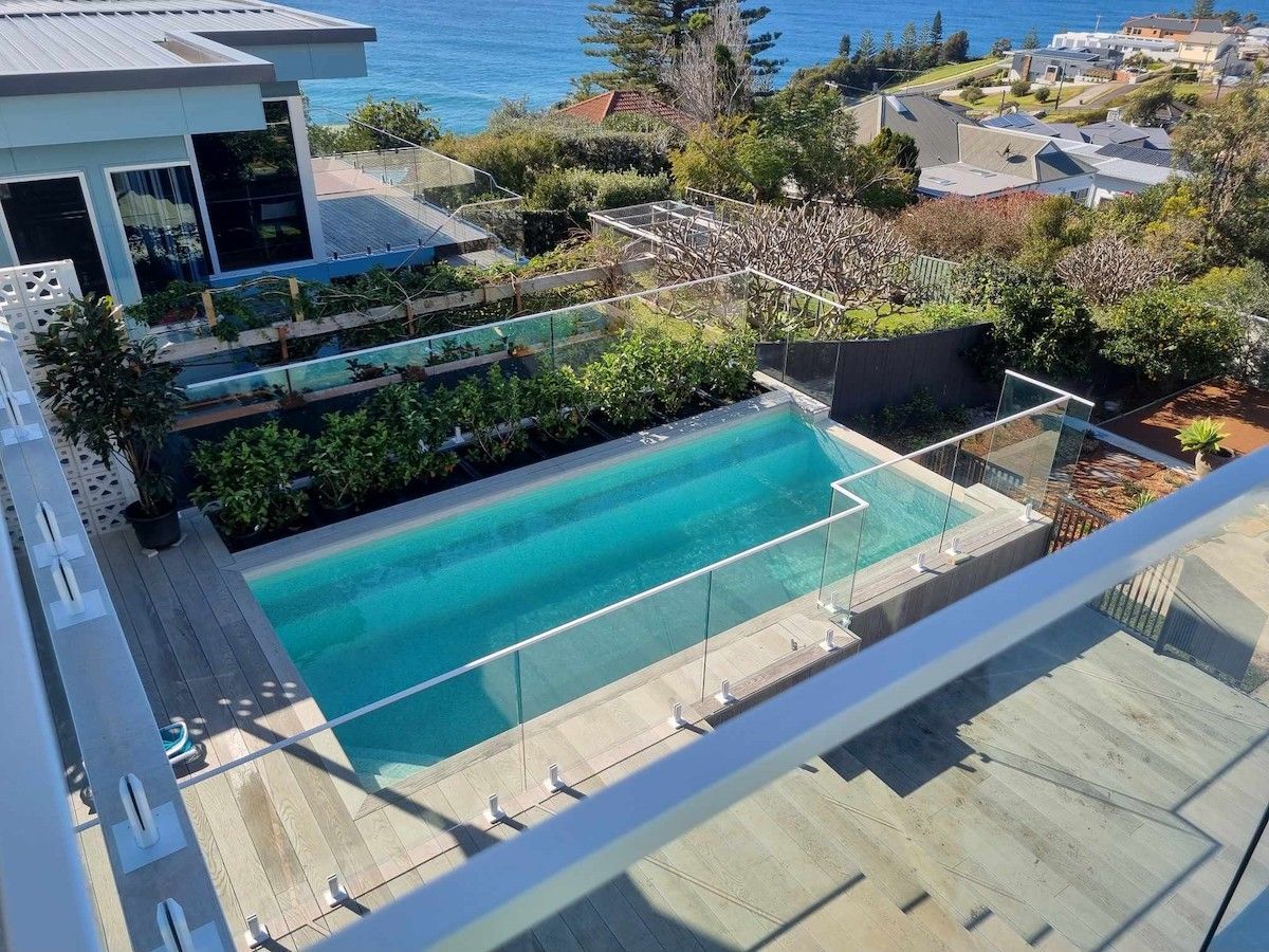 Large swimming pool surrounded by a glass fence — Pool Fence in Unanderra NSW