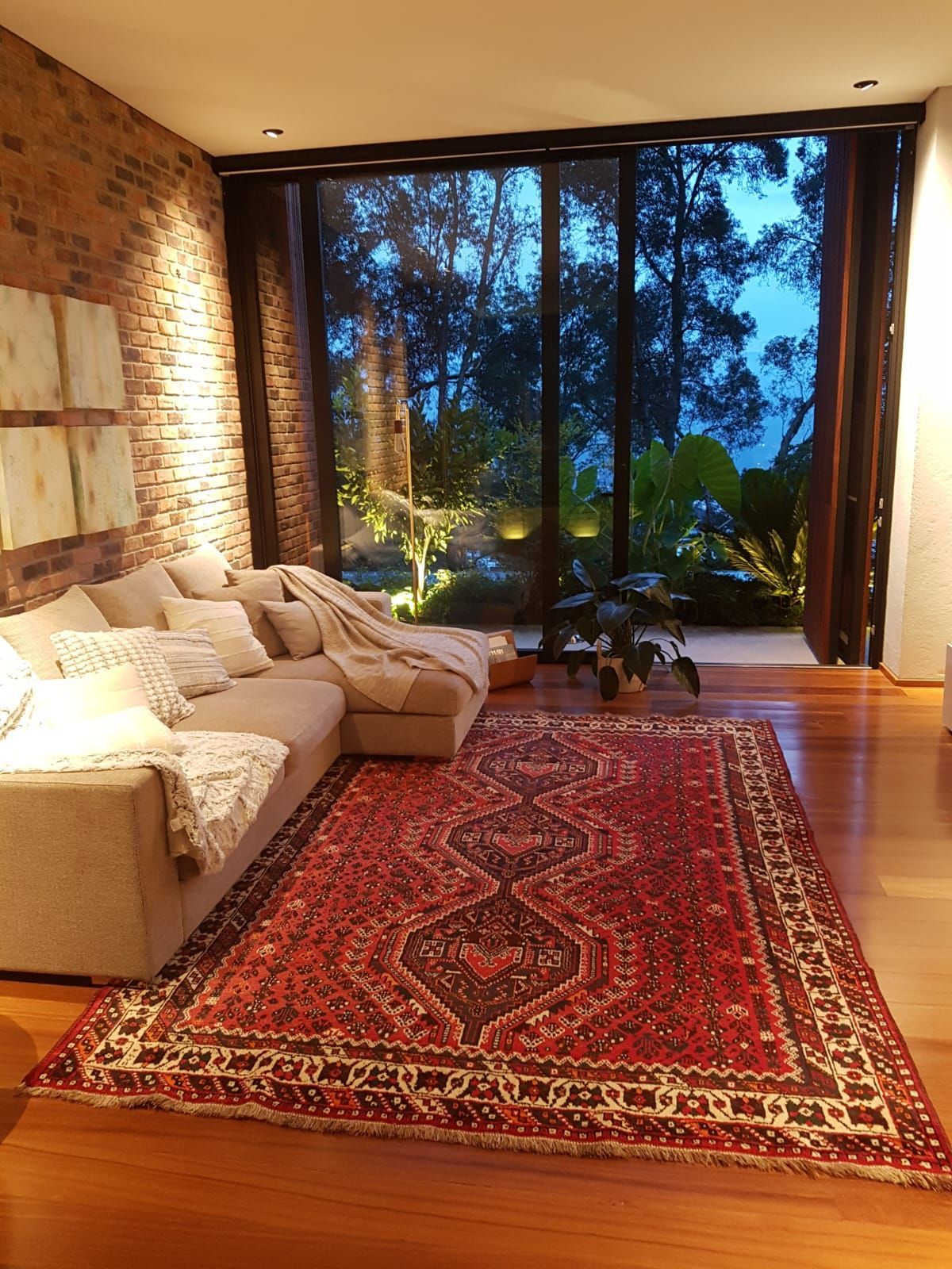 Una sala de estar con sofá, alfombra y ventana grande.