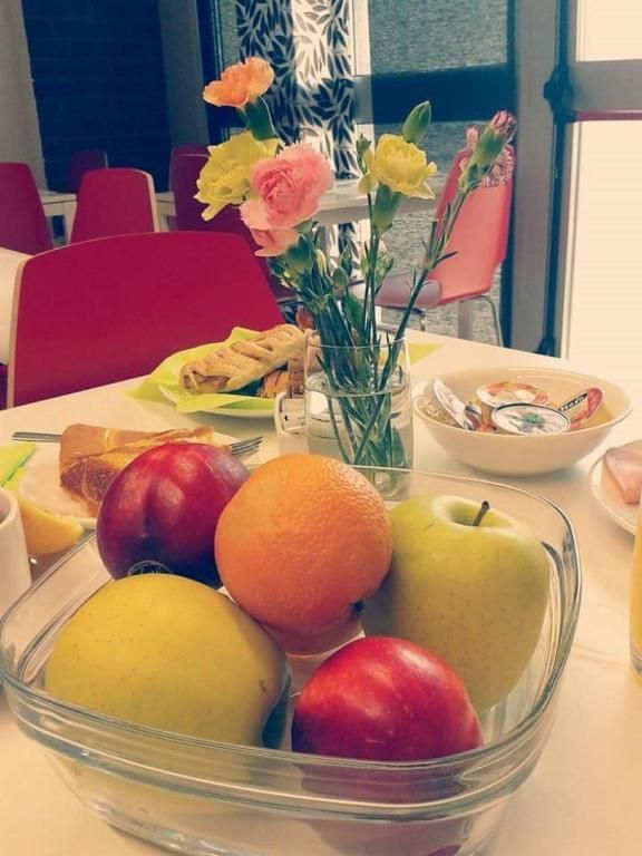 Una ciotola di frutta è appoggiata su un tavolo accanto a un vaso di fiori