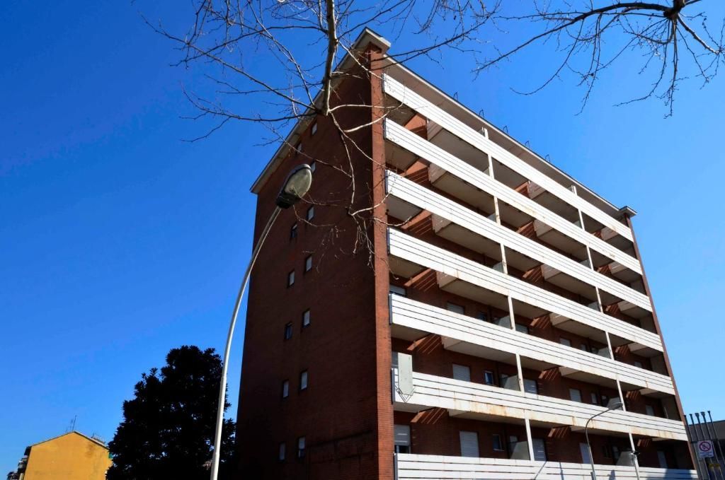 Un grande edificio in mattoni con balconi bianchi contro un cielo azzurro
