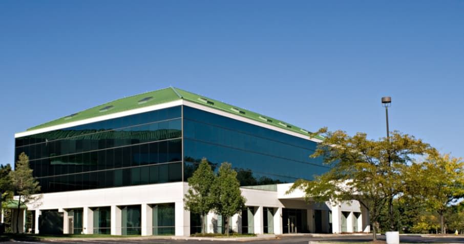 A Large Building With a Green Roof is Surrounded by Trees — TSR Tinting & Frosting in Noosa, QLD