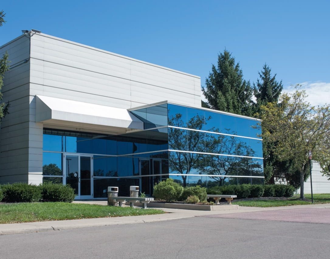 A Large Building With a Lot of Windows and Trees in Front of It — TSR Tinting & Frosting In Caloundra West, QLD