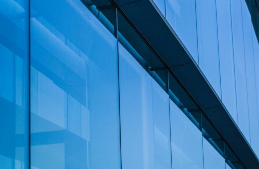 A Close Up of a Blue Glass Building With a Blue Sky Reflected in the Windows — TSR Tinting & Frosting in Caloundra, QLD