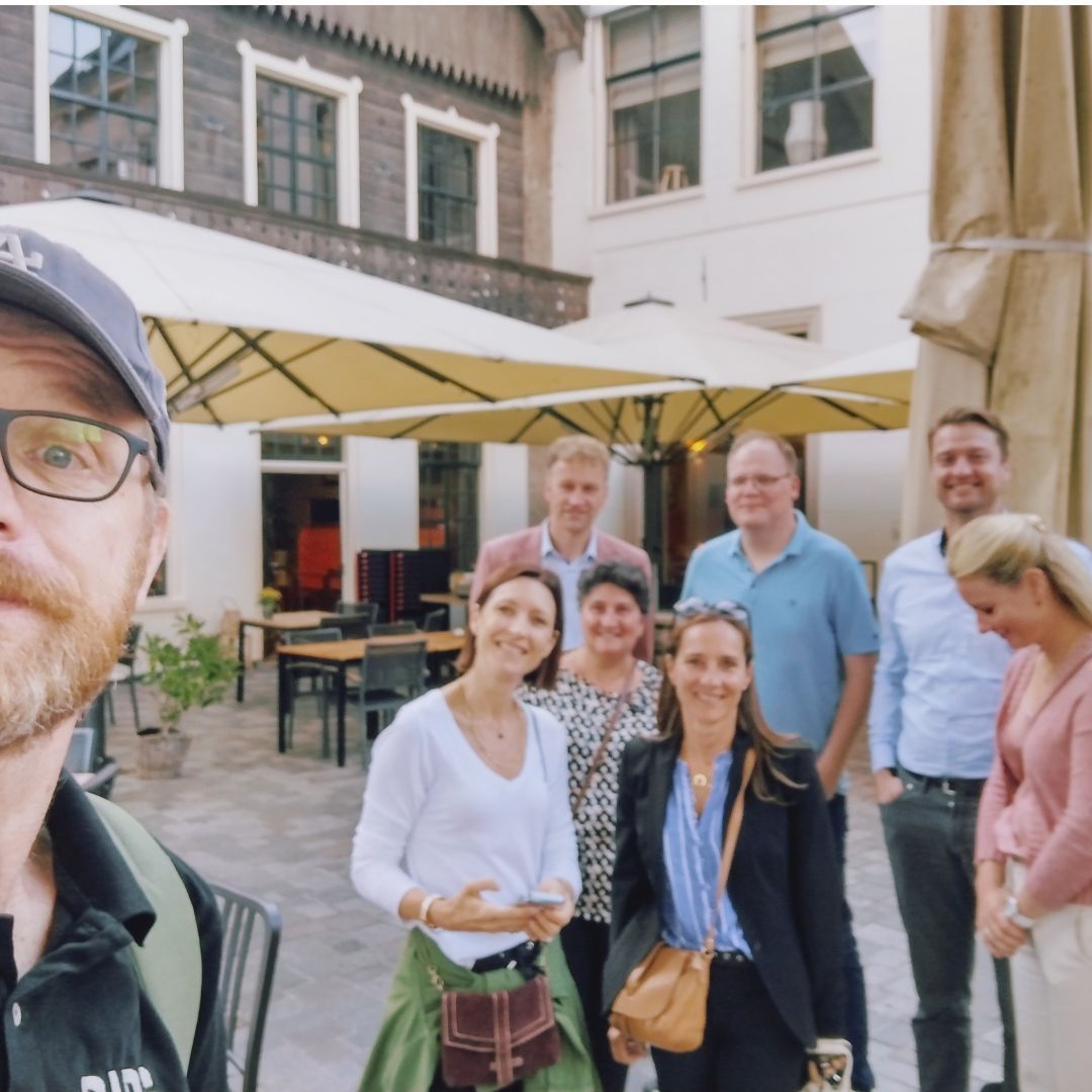 Een groep mensen die poseert voor een foto met stadsgids Groningen een man die een hoed draagt ​​met de tekst gids