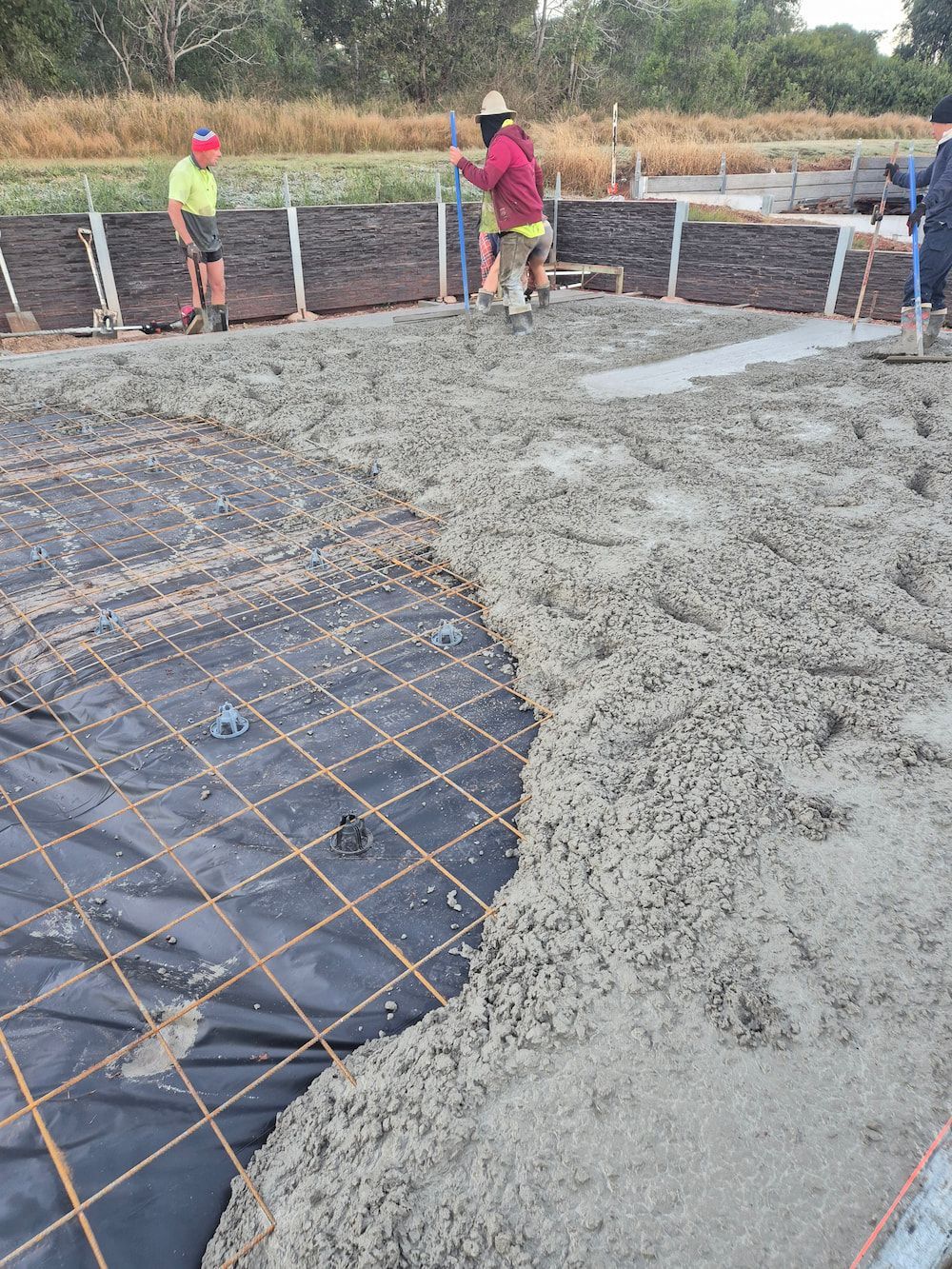 Workers Pour Concrete Over Rebar at a Construction Site Outdoors — TP Concreting In Figtree, NSW