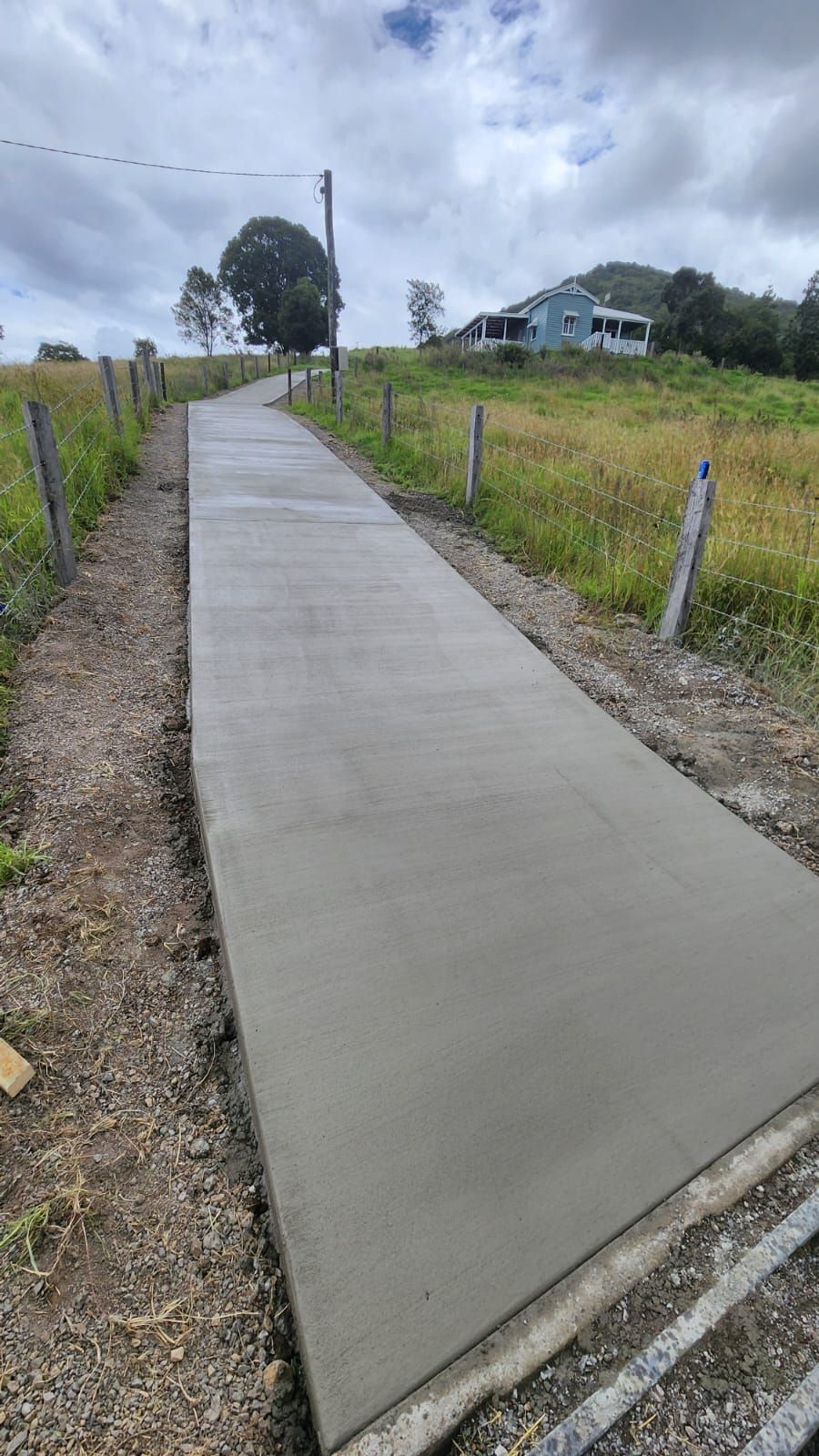 New Concrete Sidewalk Through Grassy Rural Roadside — TP Concreting In Shellharbour, NSW