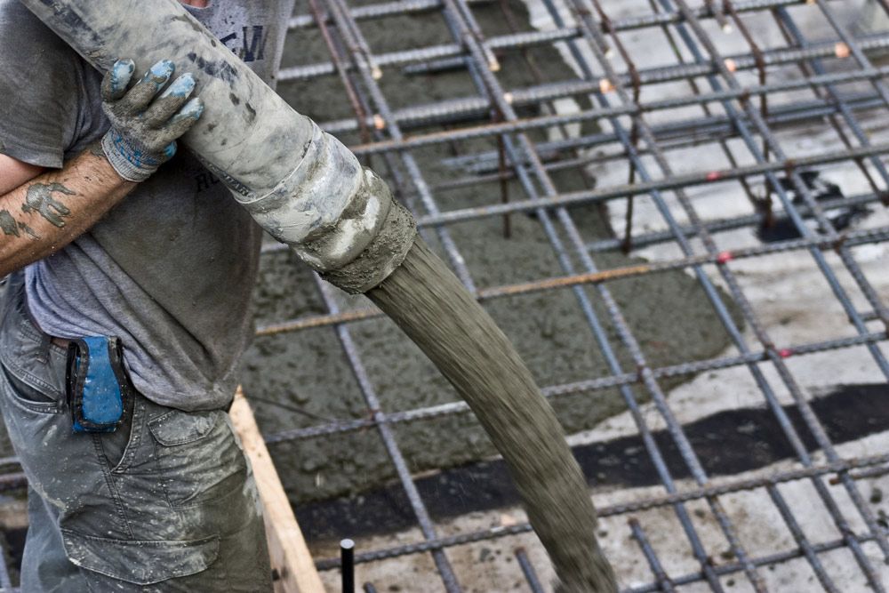 A Man Is Pouring Concrete Into A Steel Structure — TP Concreting In Nanango, QLD