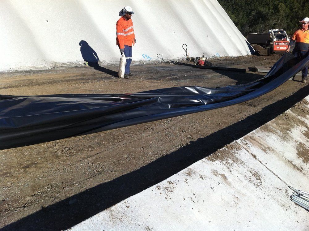A Man Is Standing In Front Of A Large White Tarp — TP Concreting In Warilla, NSW