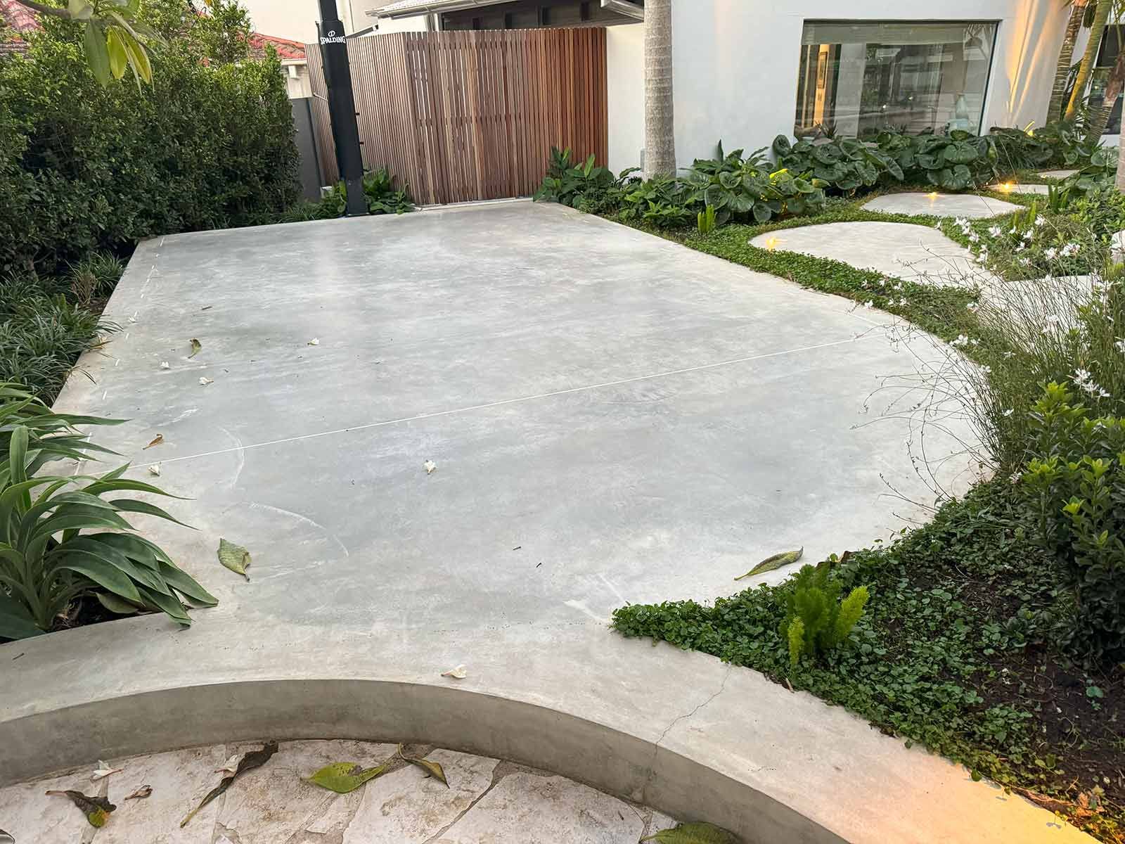 A Concrete Walkway Surrounded By Plants And Bushes In A Garden — TP Concreting In Warilla, NSW