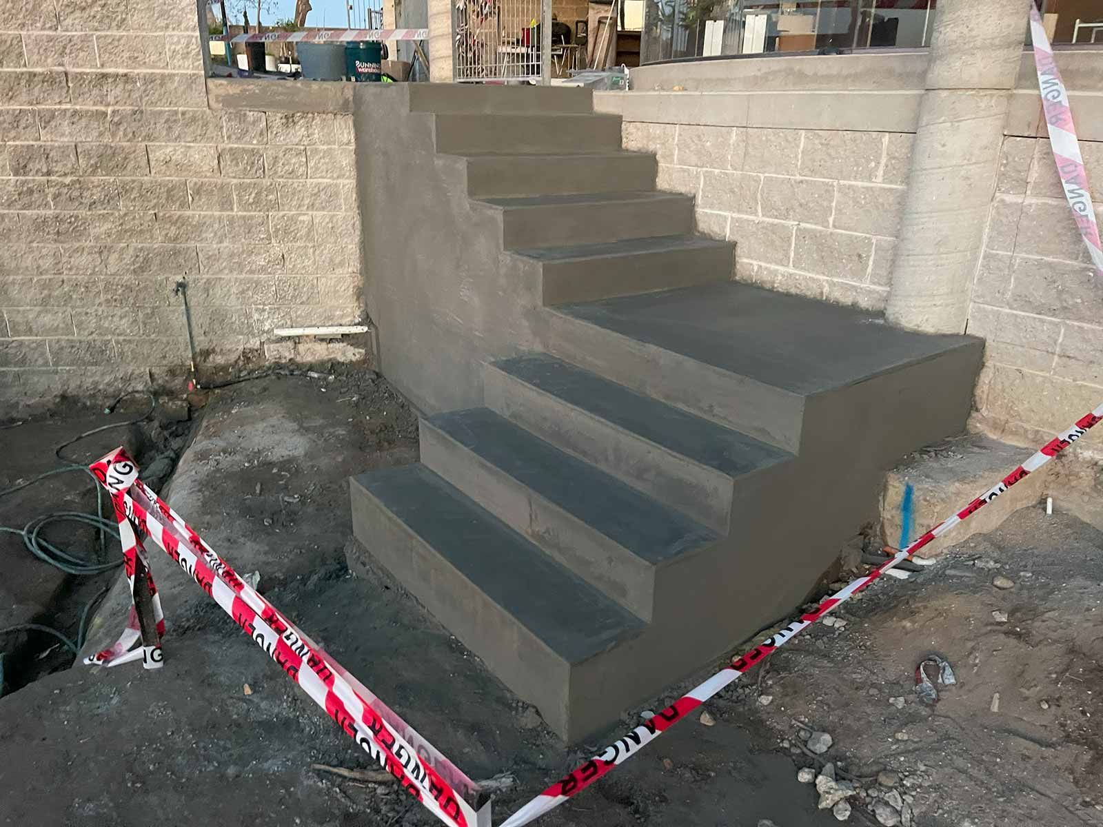 A Concrete Staircase Is Being Built Next To A Brick Wall — TP Concreting In Warilla, NSW