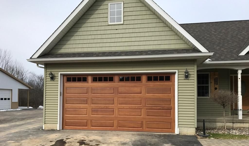 A green house with a large wooden garage door
