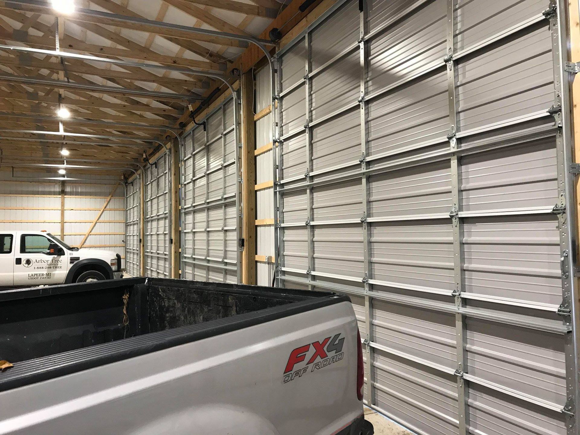A truck is parked in a garage with a large garage door.