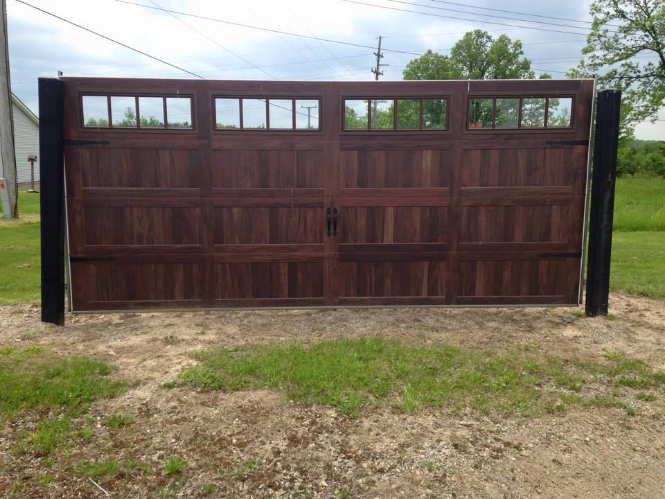 A wooden garage door is sitting in the middle of a grassy field.