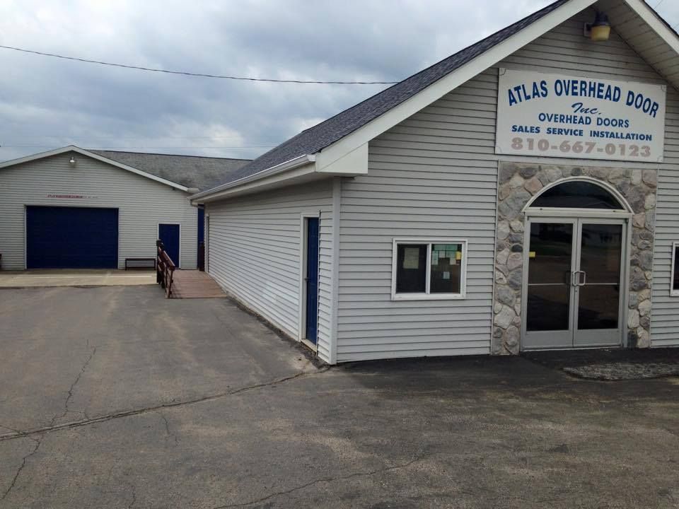 A white building with a sign that says atlas overhead doors