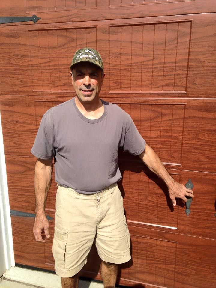 A man is standing in front of a wooden garage door.