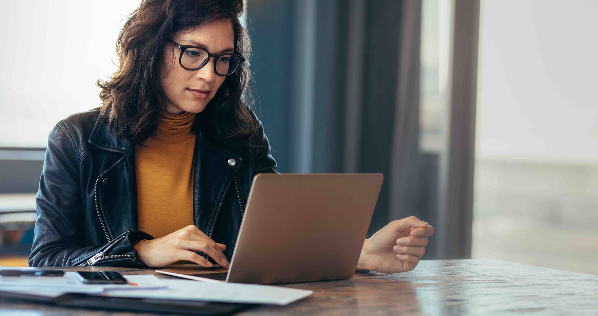 A woman is sitting at a table using a laptop computer.