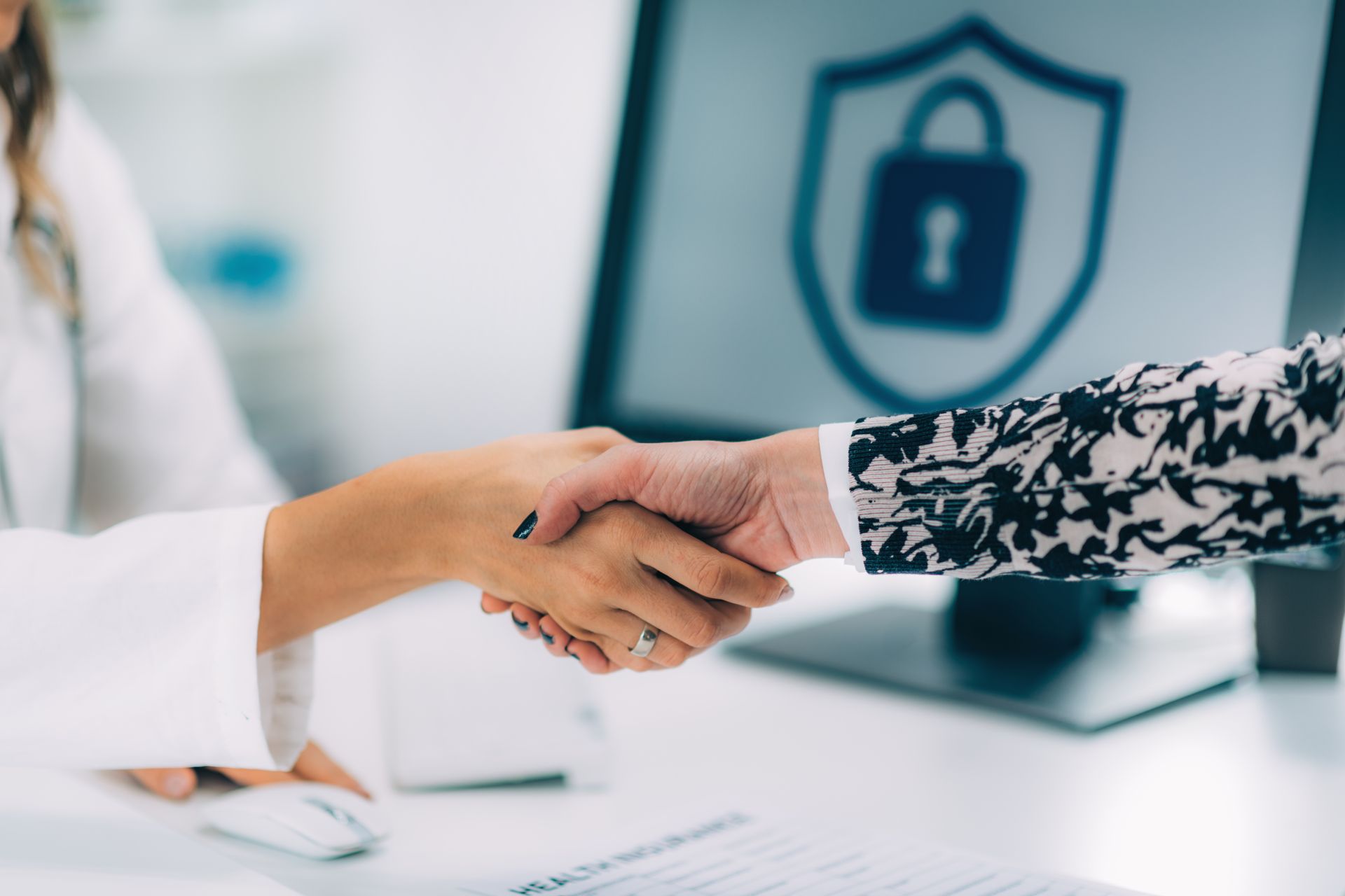 A woman is shaking hands with another woman in front of a computer.