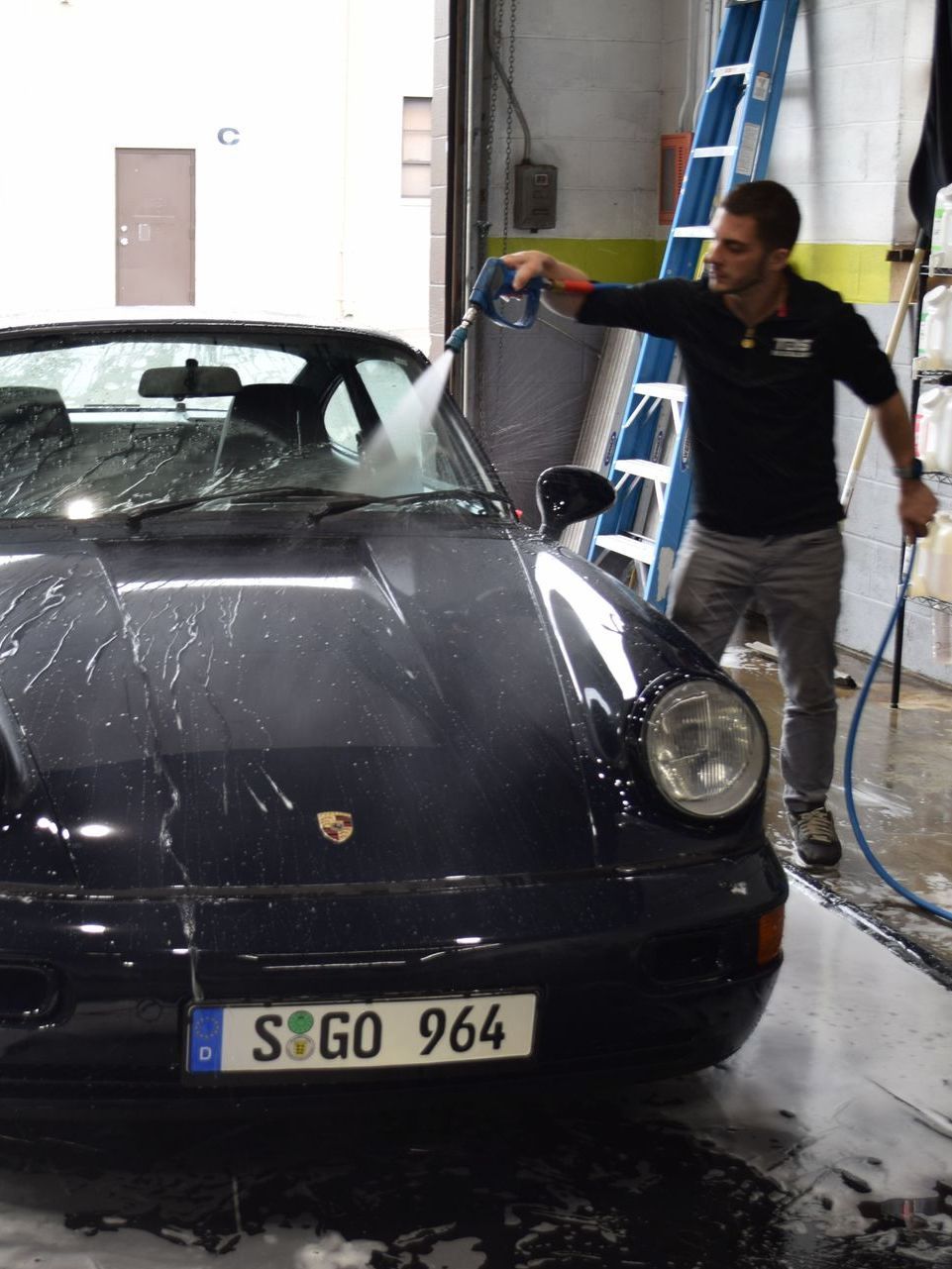 A black and white photo of a car being washed in the rain.