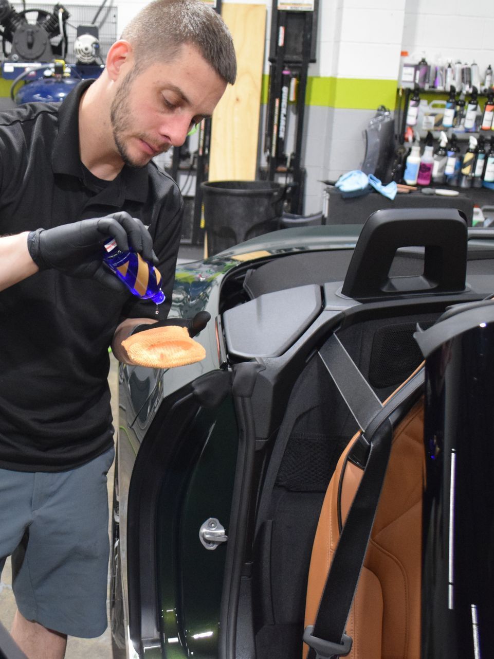 A person wearing blue gloves is cleaning a car seat