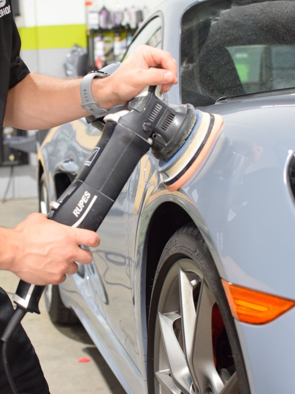 A man is polishing a car with a machine that says ruper on it