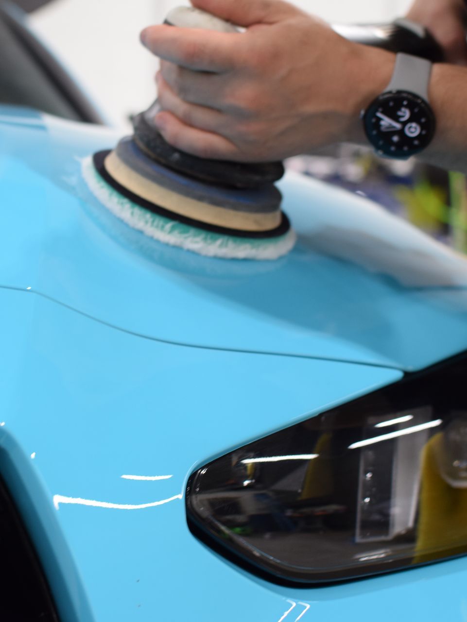 A person is polishing a car with a machine.