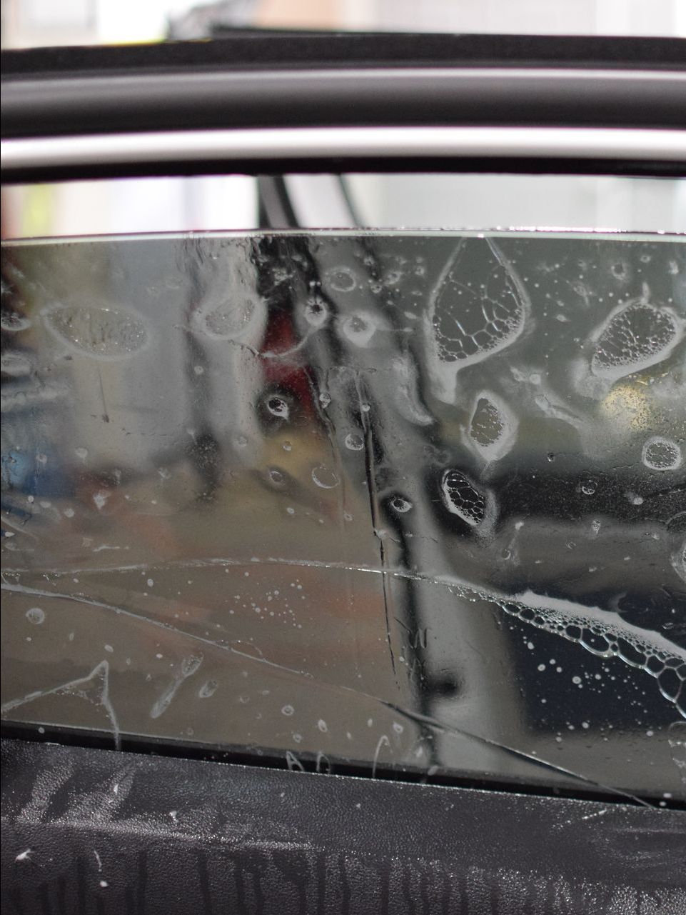 A person is applying window tinting to a car window.