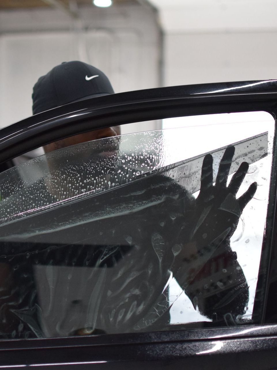 A person is cleaning a car window with a yellow sponge.