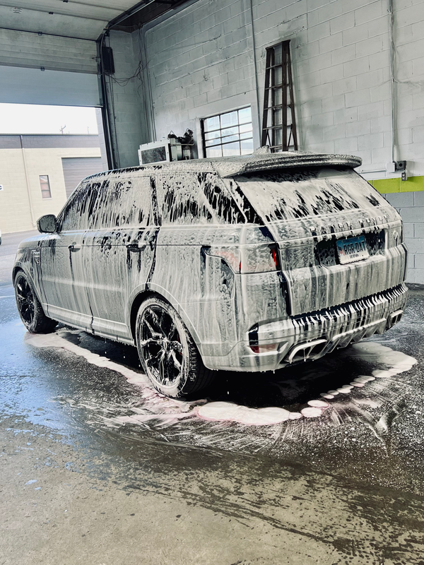 A car is covered in foam in a garage.