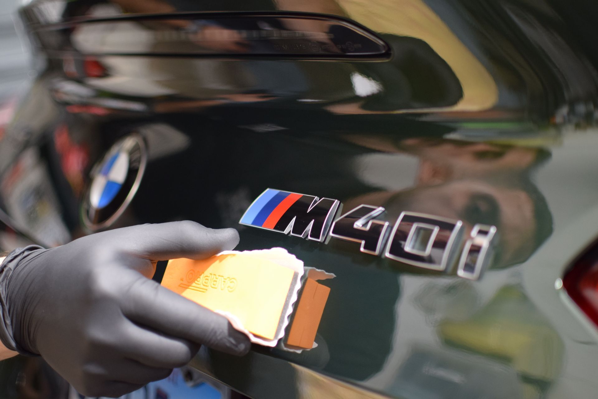 A person is applying ceramic coating to the back of a bmw.