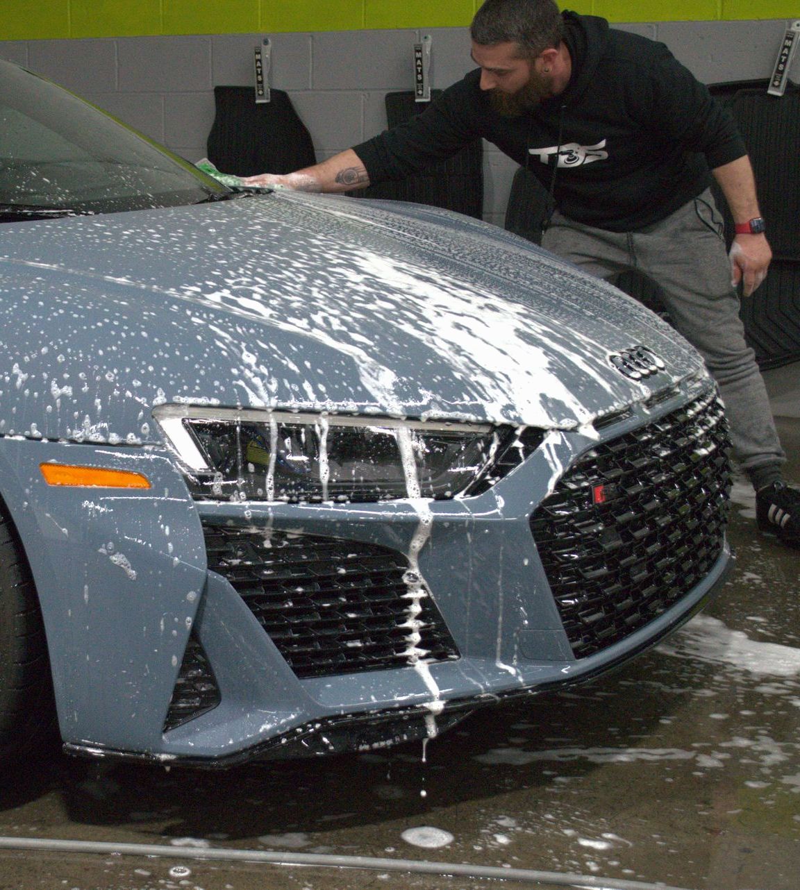 A close up of a car being washed with soap and water.