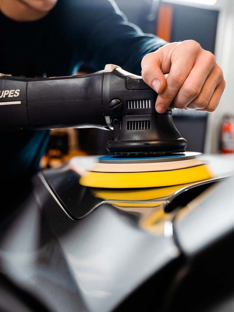 A man is polishing a car with a machine.