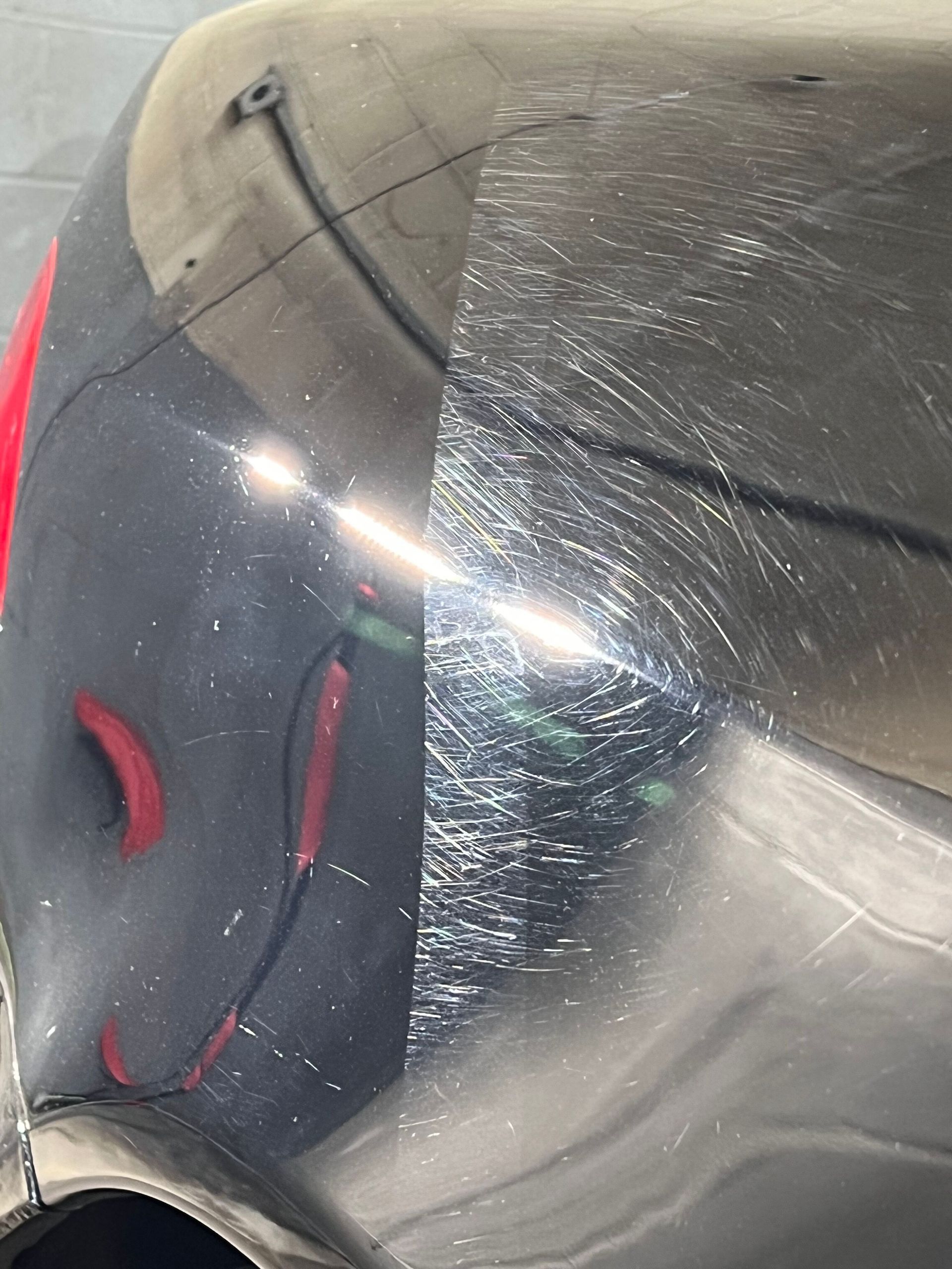 A person is polishing a red car with a machine.