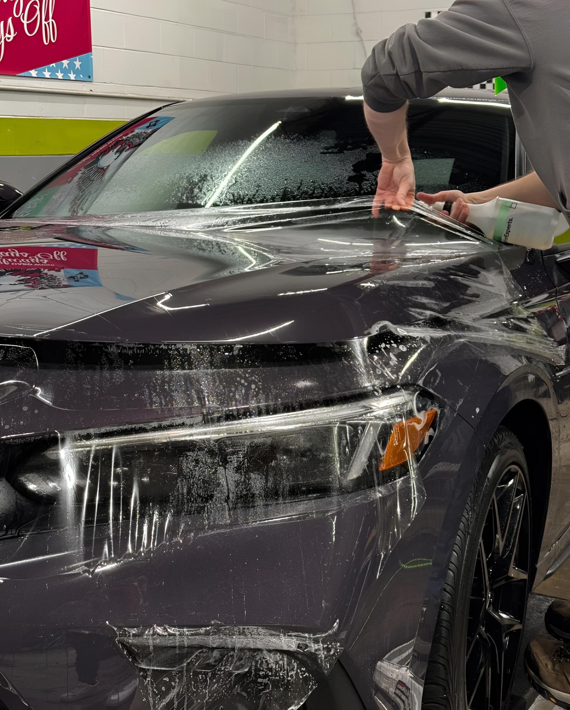 A man is polishing the hood of a car with a machine.