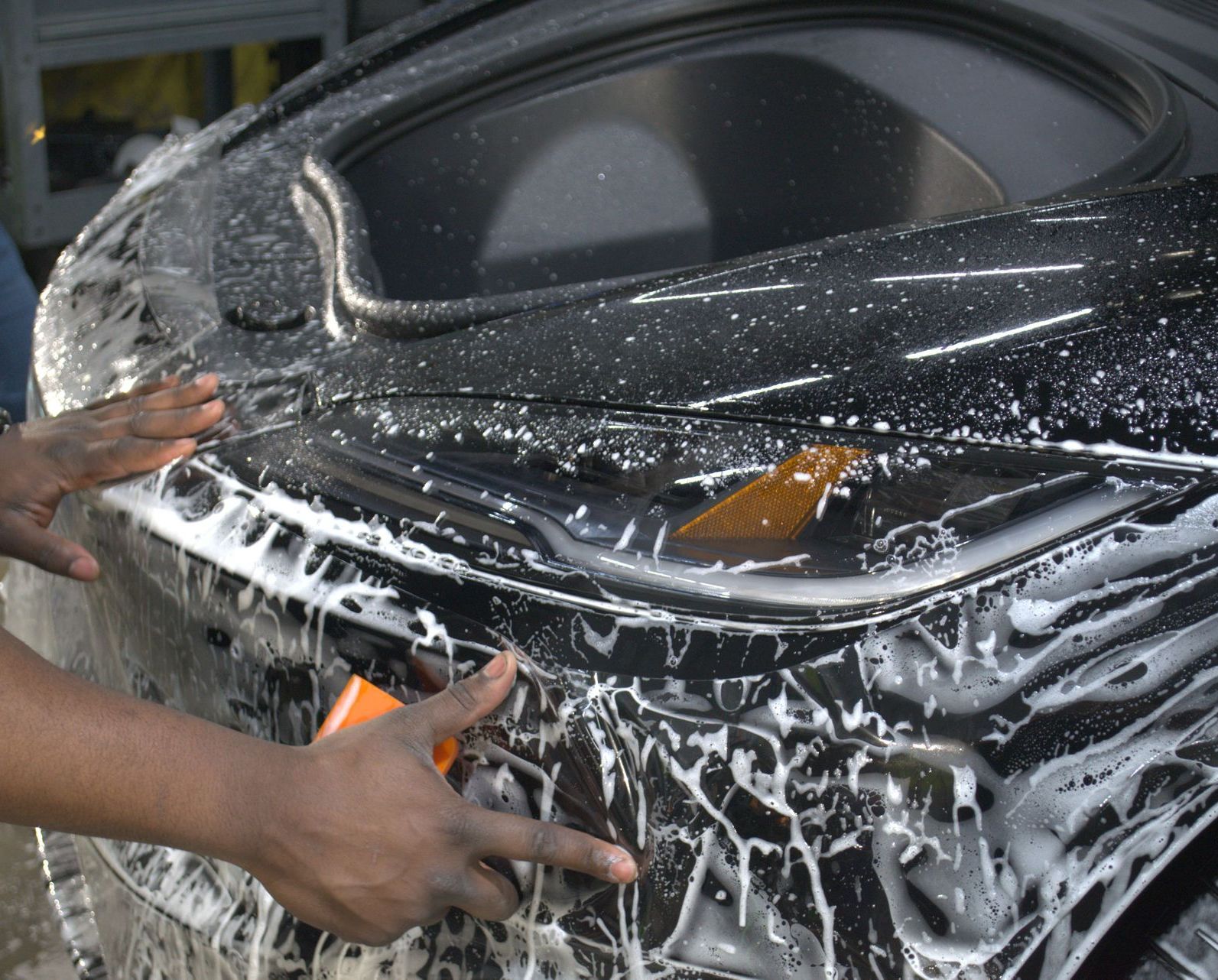 A car is being washed with soap and water at a car wash.