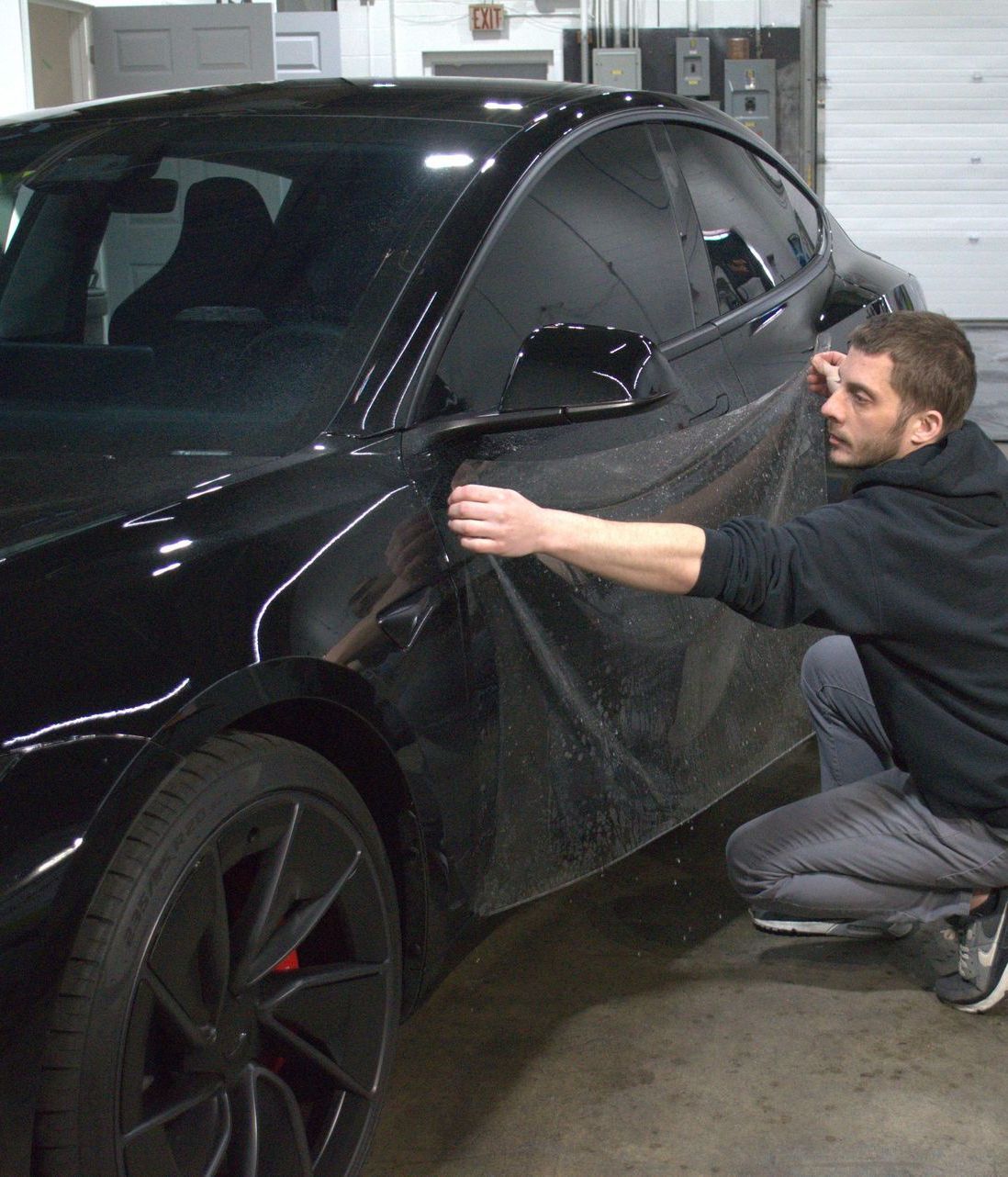 A black car with a side mirror covered in aluminum foil.