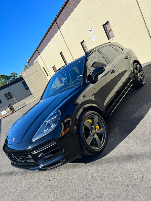 A black porsche macan is parked in front of a building