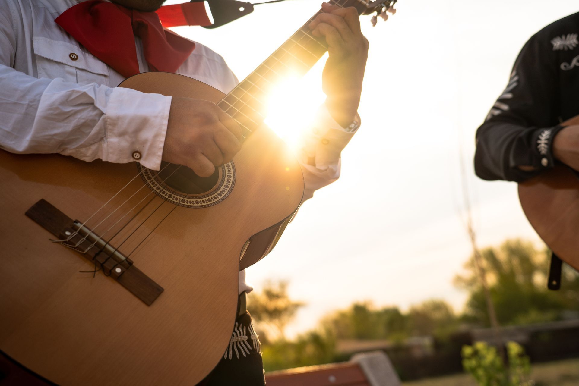 Mariachi band sitting on steps, playing instruments and laughing.