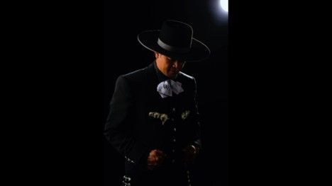 Person playing an acoustic guitar. Close-up of hands strumming strings, wearing a white shirt with red bowtie.