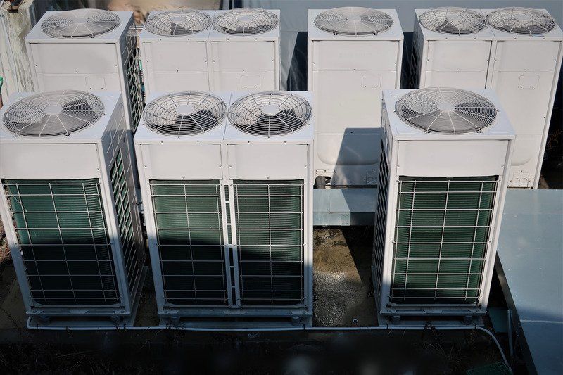 A row of air conditioners are sitting on top of a building.