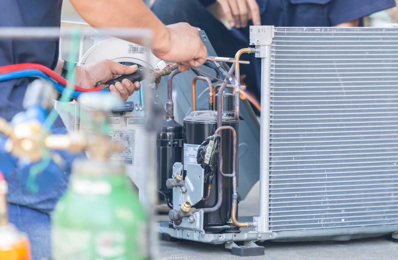 A man is working on an air conditioner with a welding machine.