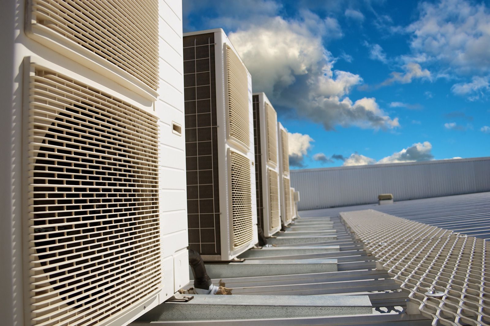 A row of air conditioners are lined up on the side of a building.