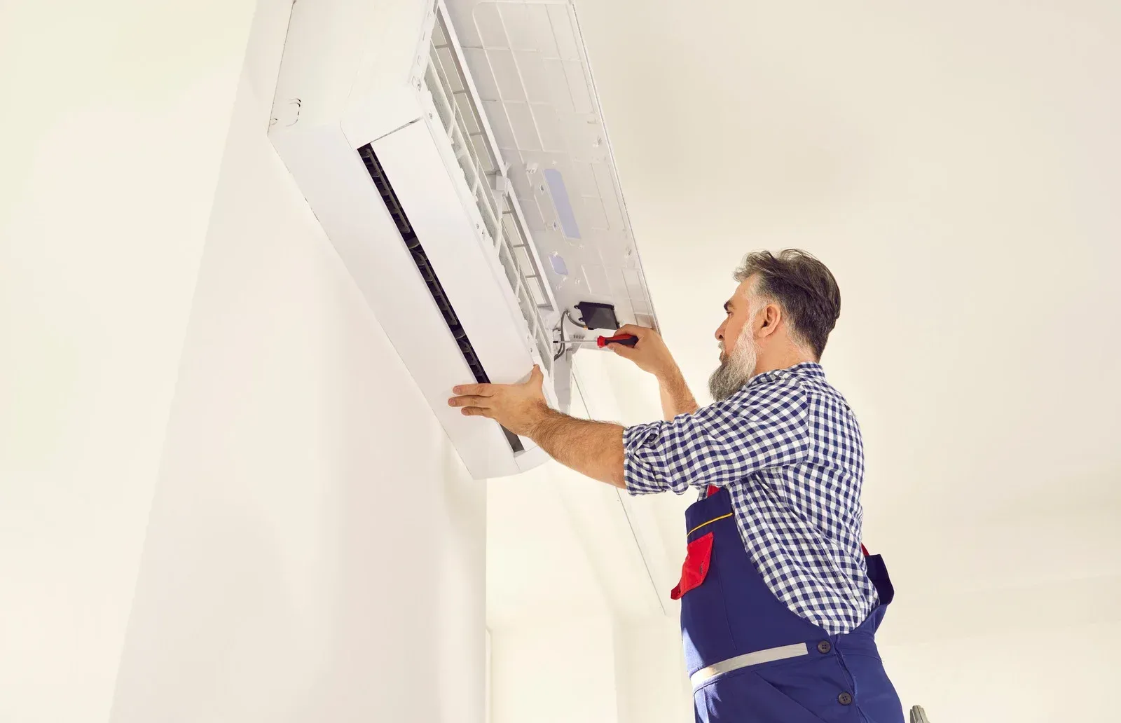 A man is installing an air conditioner on the wall.