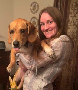 A woman is holding a brown dog in her arms.