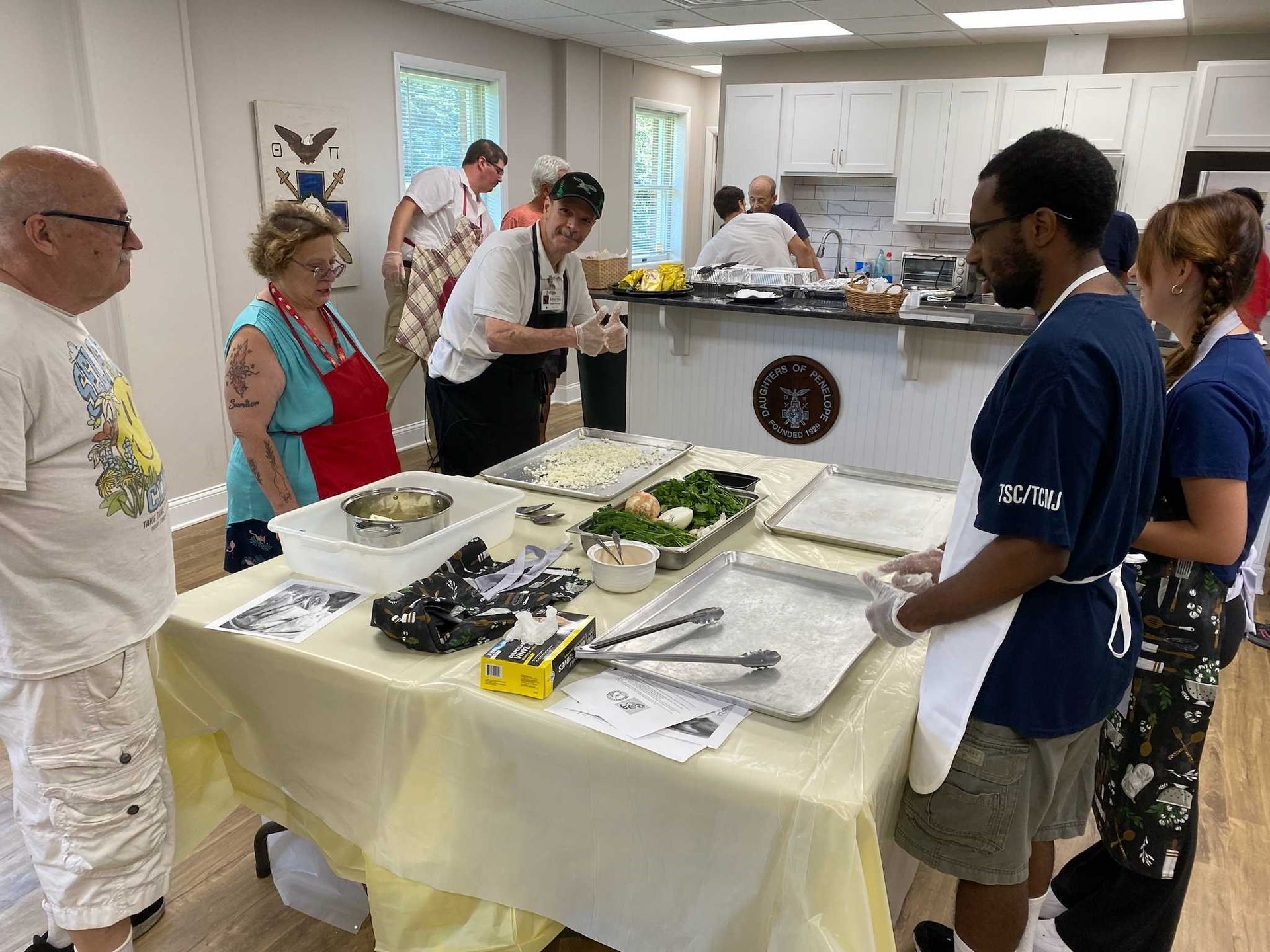 A group of people are standing around a table in a kitchen.