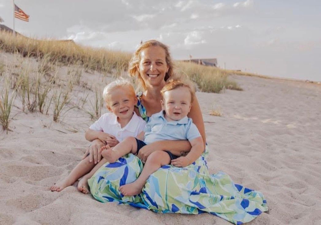 A woman wearing glasses and braids is smiling for the camera