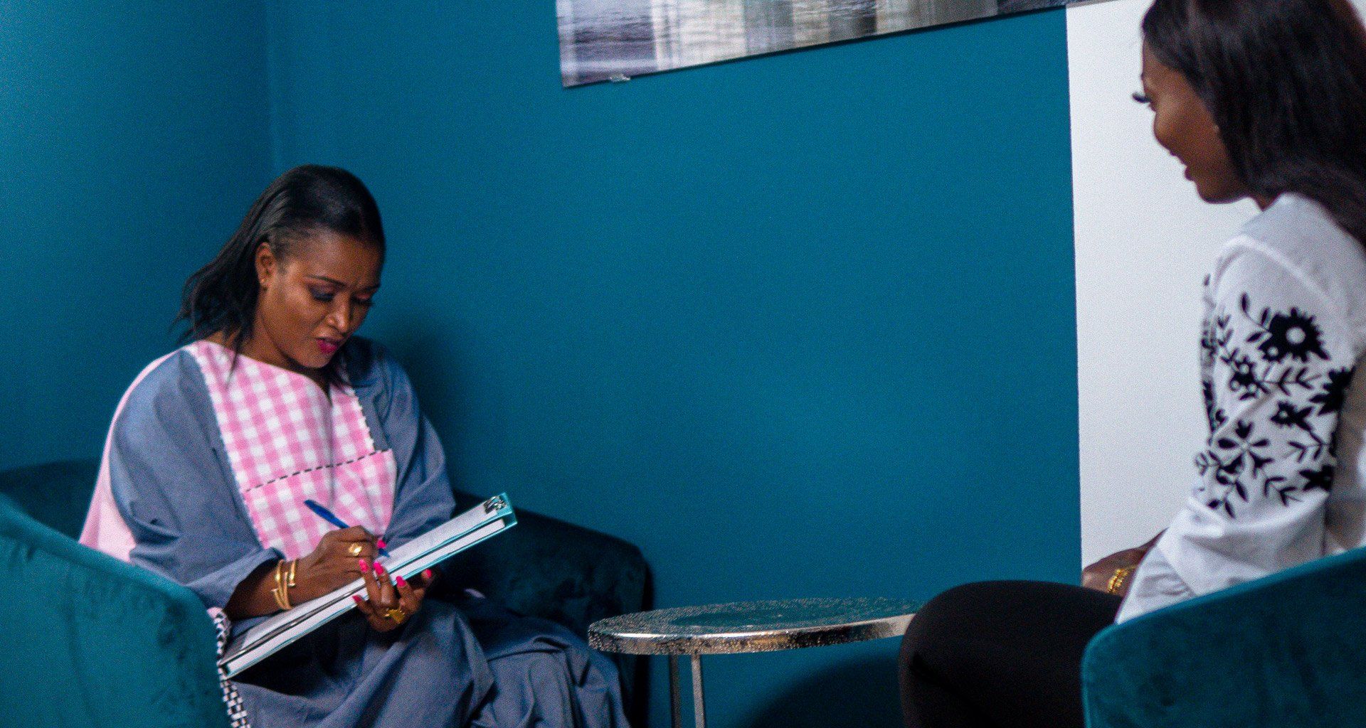 Une femme est assise sur un canapé et parle à une autre femme.