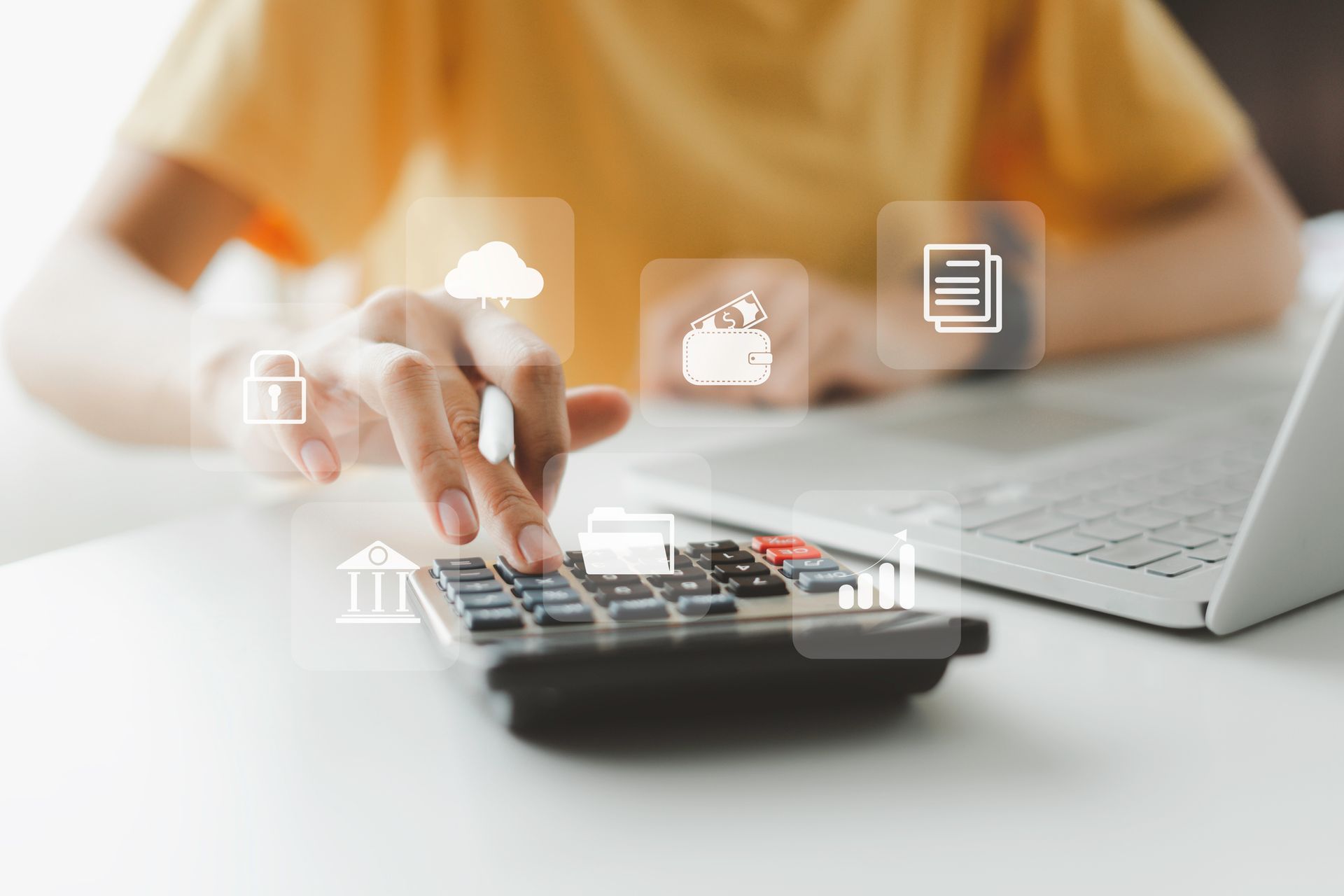 A person is using a calculator in front of a laptop computer.