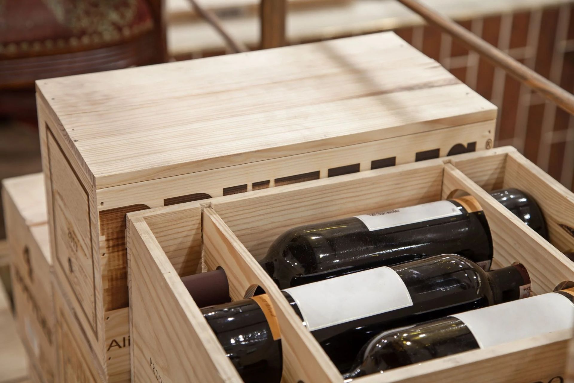 Cassa di legno per vino con bottiglie di vetro su un ripiano, una delle quali aperta per mostrare le bottiglie all'interno.