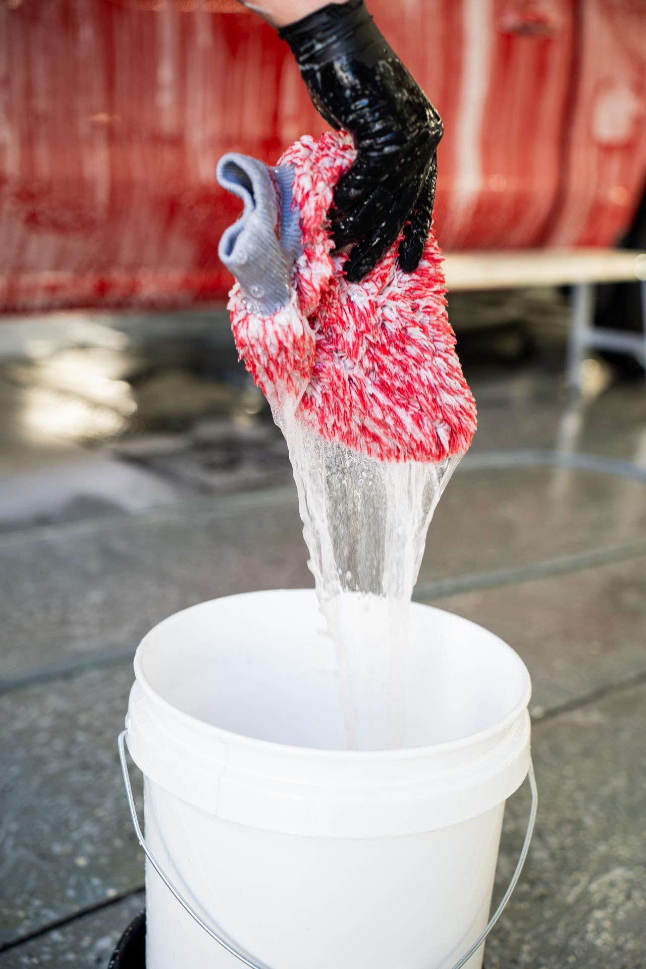 Full Detailing - A person is pouring water into a bucket.